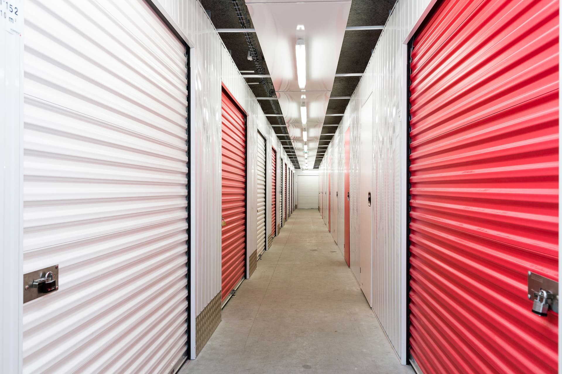 Couloir intérieur avec rangées de portes de boxes rouges et blanches du centre HOMEBOX Thonon-les-Bains